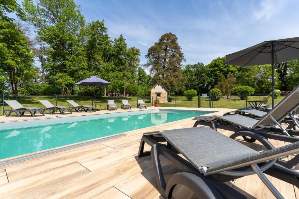 a swimming pool with chairs and umbrellas in front at Gite Chateau 3 chambres piscine chauffée in La Châtelaine