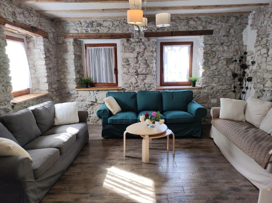 a living room with a blue couch and a table at Casa di Volce - 1801 Stone House in Tolmin