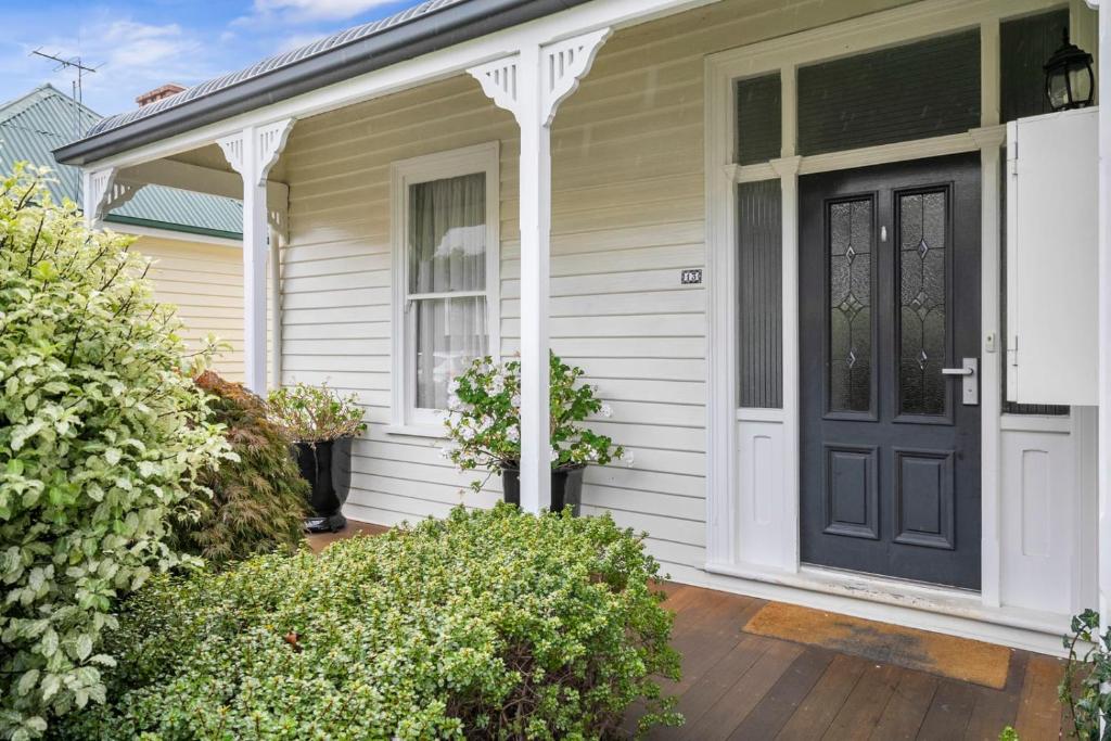une maison avec une porte noire sur une terrasse couverte dans l'établissement Stunning newly renovated home in perfect location, à Hobart