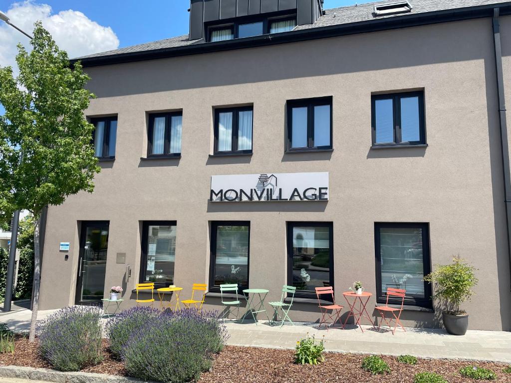 Hotel Monvillage في Mondercange: مبنى امامه كراسي وطاولات