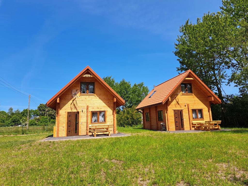 un par de casas de troncos en un campo en Słoneczne Zacisze, en Smołdzino