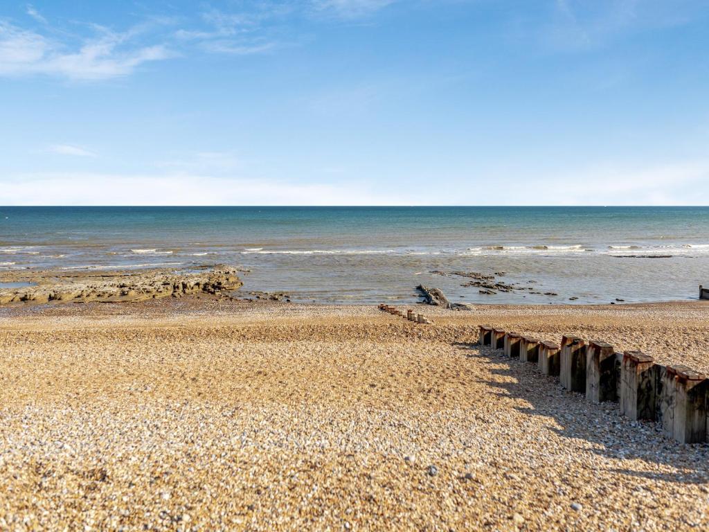 a beach with a pier and the ocean at Crossways Mansions in Bexhill