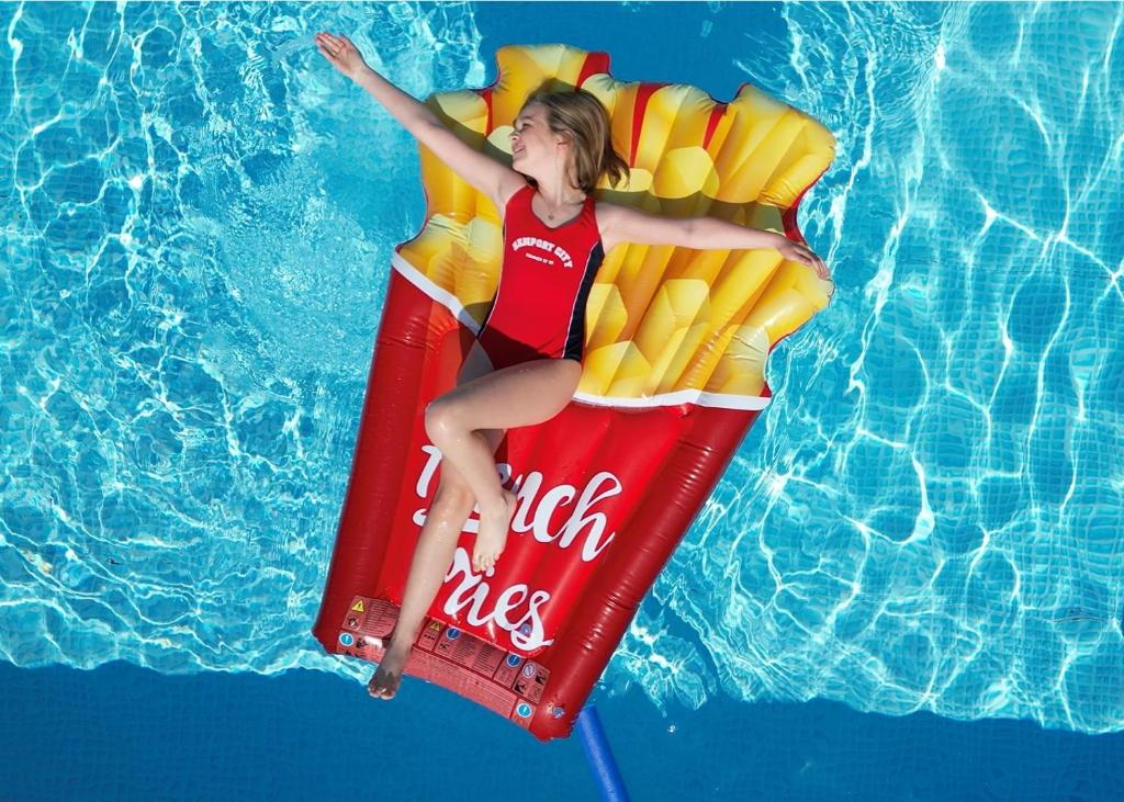 a woman is laying on a coke coke raft in a pool at Holiday-Camp in Rusinowo