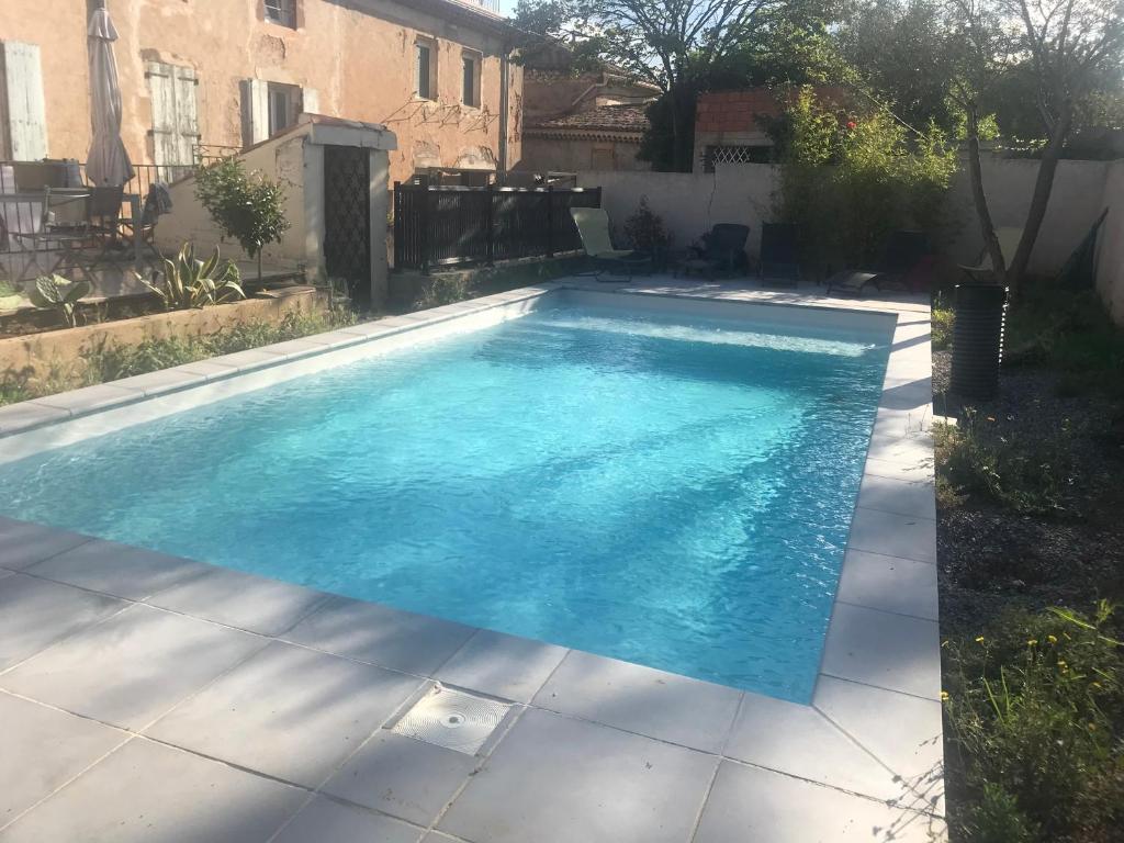 een zwembad met blauw water in een achtertuin bij Douceur occitane in Saint-Chinian