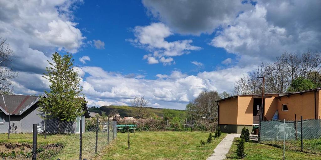 a field with a building and a blue sky with clouds at Ubytovanie v súkromí in Dolné Plachtince