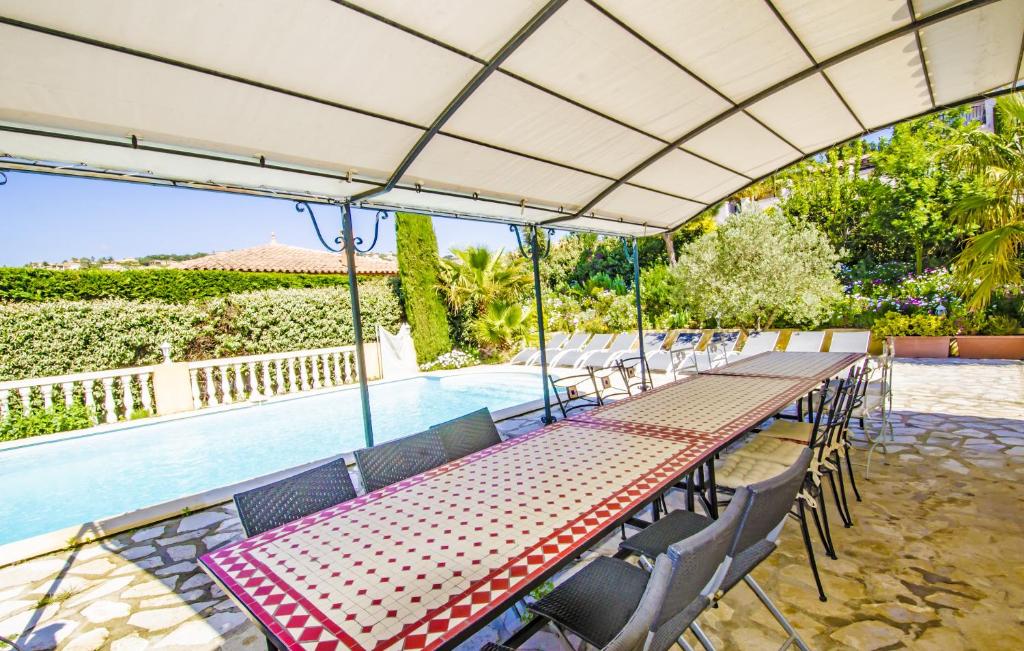 a long table with chairs next to a pool at Grande Villa à Sainte Maxime - Golfe de Saint Tropez in Sainte-Maxime