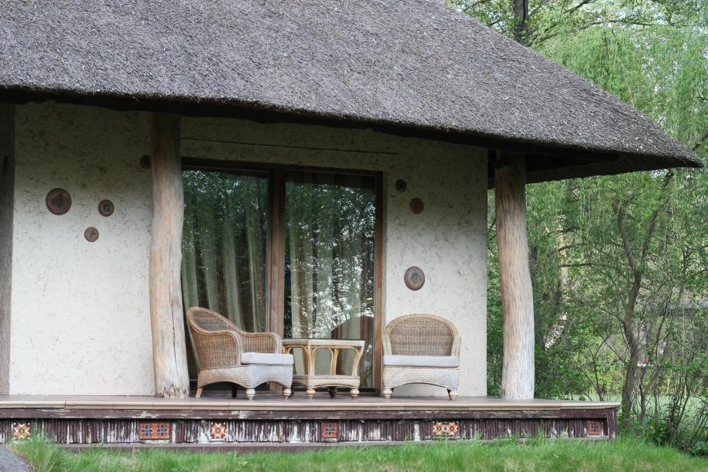 佩列亚斯拉夫-赫梅利尼茨基Secret Resort Club的一个带椅子和茅草屋顶的房屋门廊