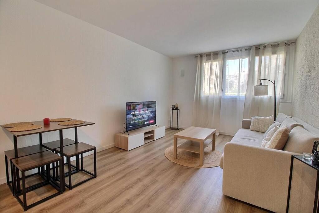 a living room with a couch and a tv at Bulle de bonheur ! Appartement avec deux chambres in Colombes