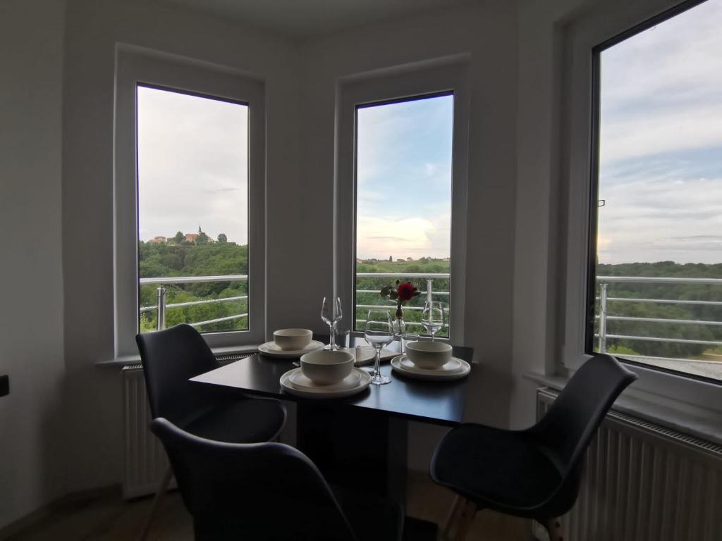 a dining room with a table and chairs and two windows at Apartma KORPEC in Ivanjkovci