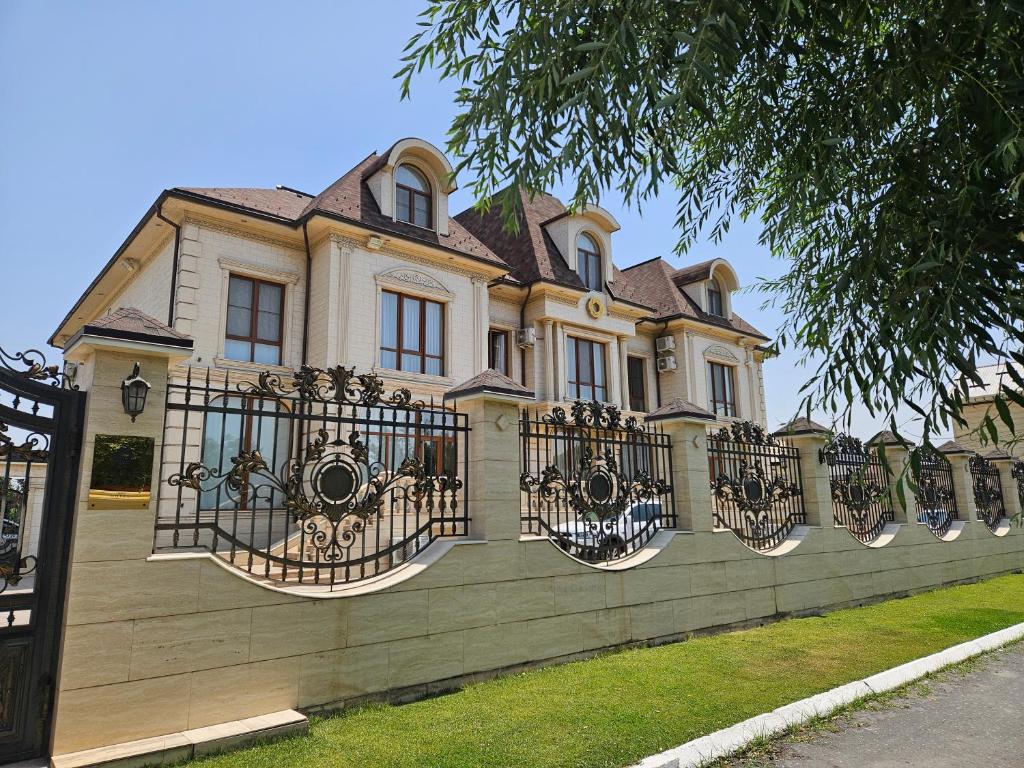 a large house with a fence in front of it at Silk Road Kokand Hotel in Kokand