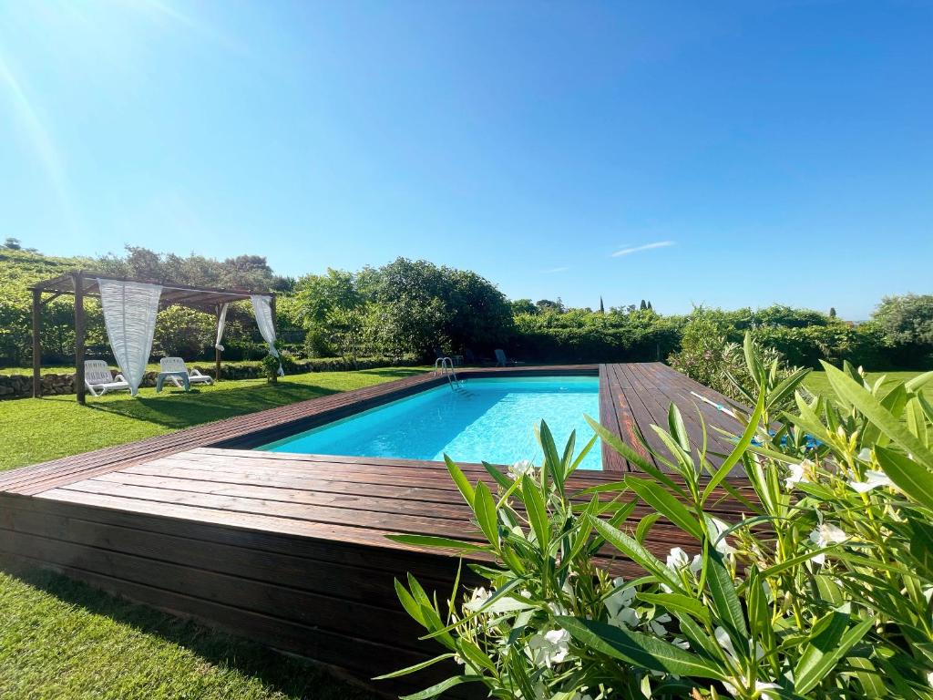 a swimming pool with a wooden deck next to a yard at Relais Valpolicella B&B in Marano di Valpolicella