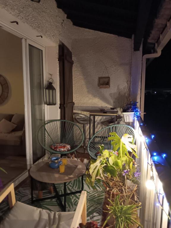 Un balcón con 2 sillas y una mesa con luces. en Chez kary, en Saint-Cyr-sur-Mer