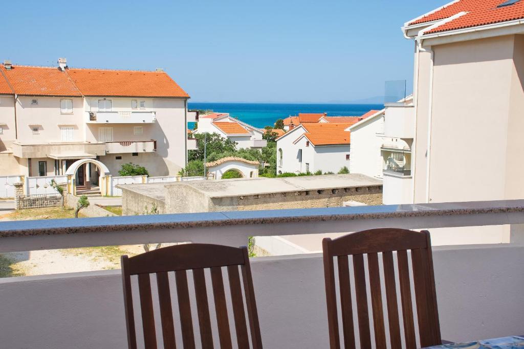 two chairs sitting on a balcony with a view of buildings at Apartments Summersong in Novalja