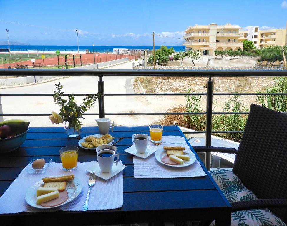einen blauen Tisch mit Tellern und Strandblick in der Unterkunft Stadium Sea Beach Apartment in Kissamos