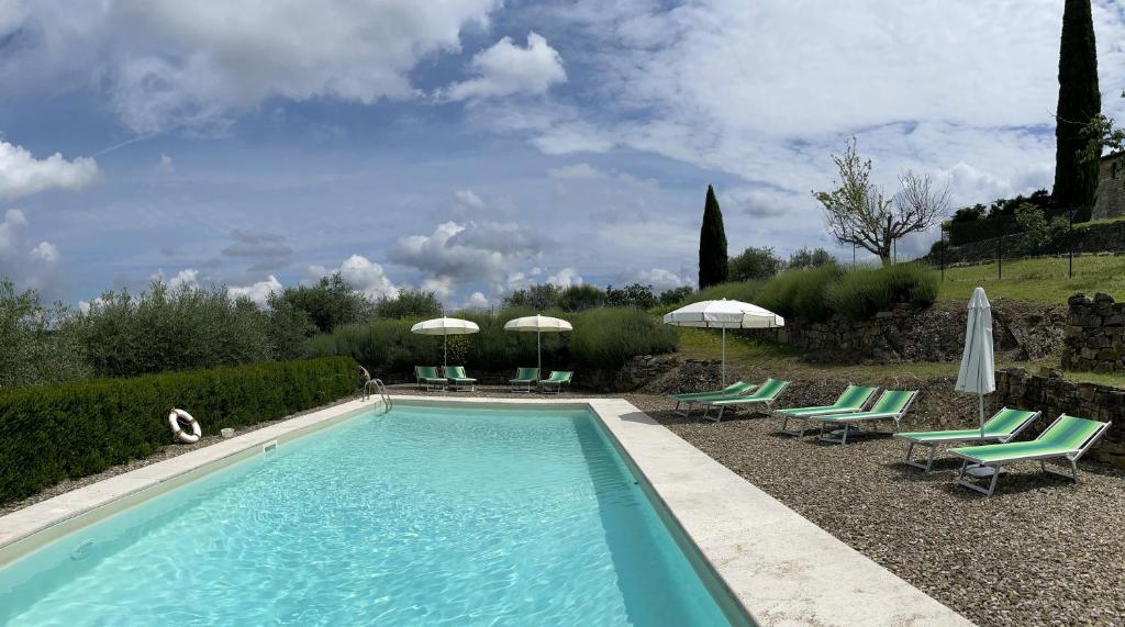 a swimming pool with lawn chairs and umbrellas at Torre Di Ponzano in Barberino di Val dʼElsa