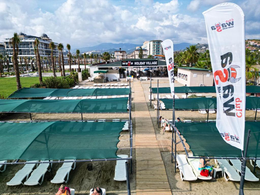 una playa con un montón de sillas y tiendas de campaña en Club Wasa Holiday Village All Inclusive, en Toslak