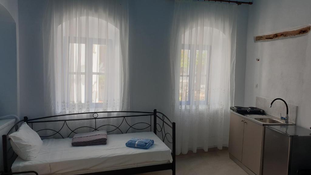 a bedroom with a bed with two windows and a sink at Stathis Apart 2 in Amorgos