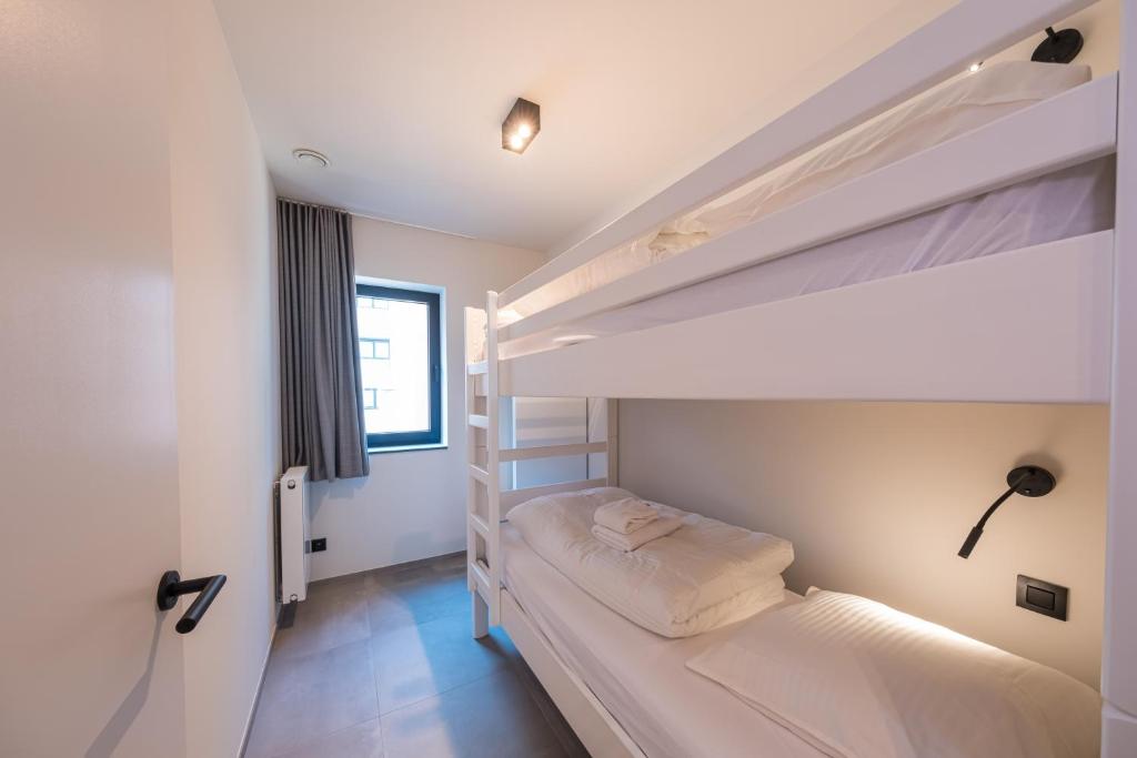 a bedroom with two bunk beds and a window at Belcasa Mar Suites & Lofts in Middelkerke