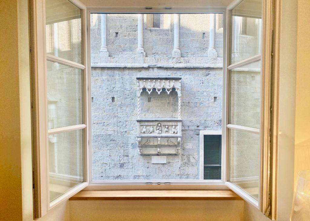 een open raam met uitzicht op een bakstenen gebouw bij Amazing San Lorenzo 19 - Rolli Palace - Overlooking Cathedral with Free Private Parking included! in Genua