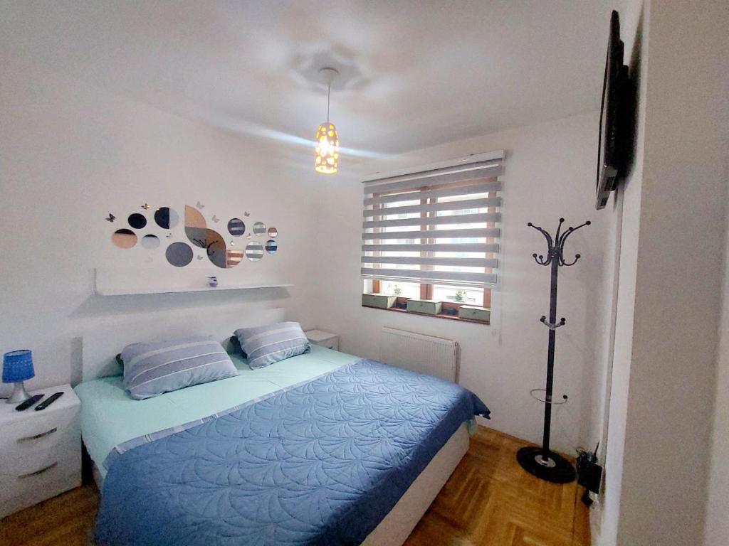 ein Schlafzimmer mit einem blauen Bett und einem Fenster in der Unterkunft Apartman Teo in Lukavica