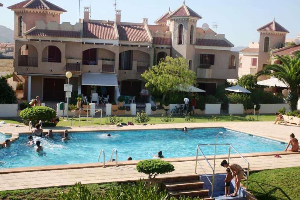 une piscine en face d'un grand bâtiment dans l'établissement Precioso dúplex con piscina, en 1ª linea de playa, à Puerto de Mazarrón