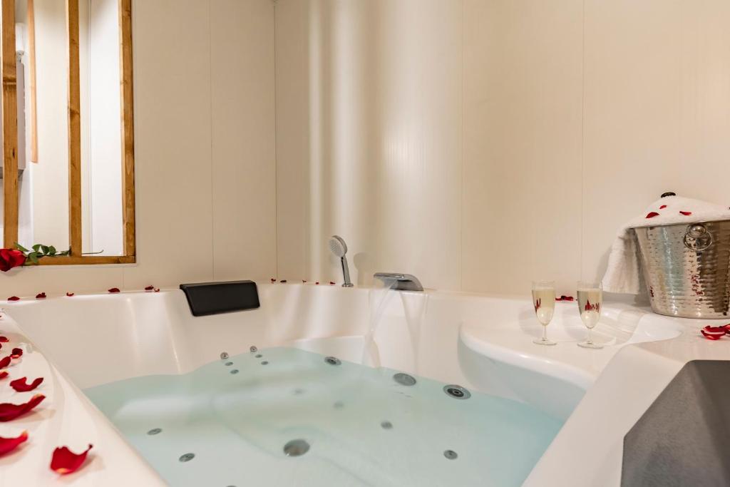 a white bathroom with a tub and two glasses of wine at Bali Chic in La Hourcade