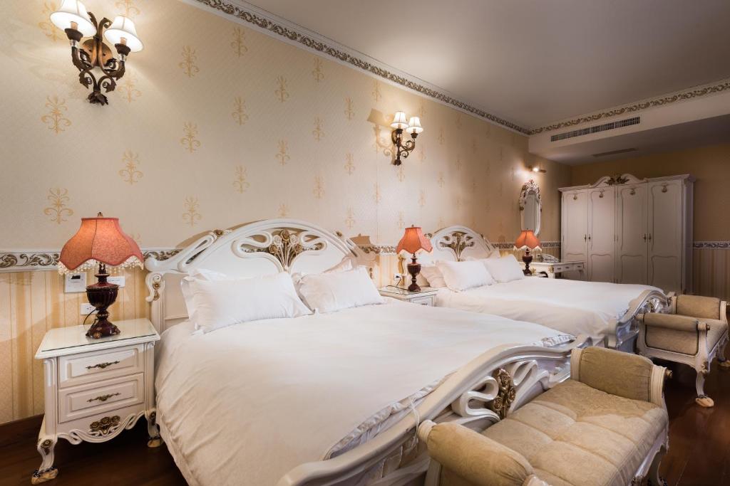 two beds in a bedroom with two chairs and lamps at Cingjing Florence Resort Villa in Ren&#39;ai