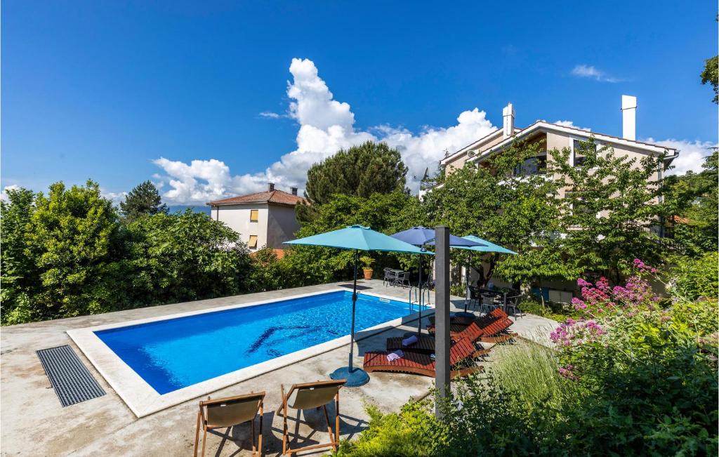 a swimming pool with chairs and umbrellas next to a house at Beautiful Home In Spincici With Kitchen in Kastav