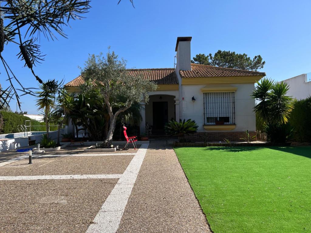 una casa con un césped verde delante de ella en Habitación con baño Malva, en Lepe