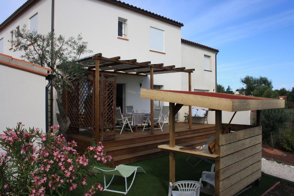une cour arrière avec une terrasse en bois avec une table et des chaises dans l'établissement Gite du Llevan, à Sorède