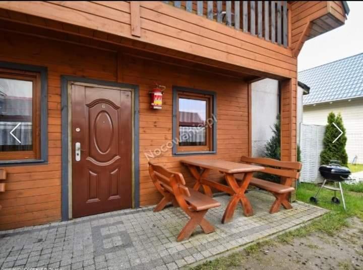 a wooden cabin with a picnic table and two benches at Olimp Resort in Sarbinowo