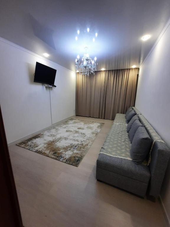 uma sala de estar com um sofá e uma televisão em Жк Сити плюс em Almaty