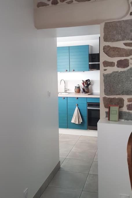 une cuisine avec des placards bleus et un mur en pierre dans l'établissement La maison aux Hortensias, 1km de la plage, proche du sillon de Talbert, à Pleubian