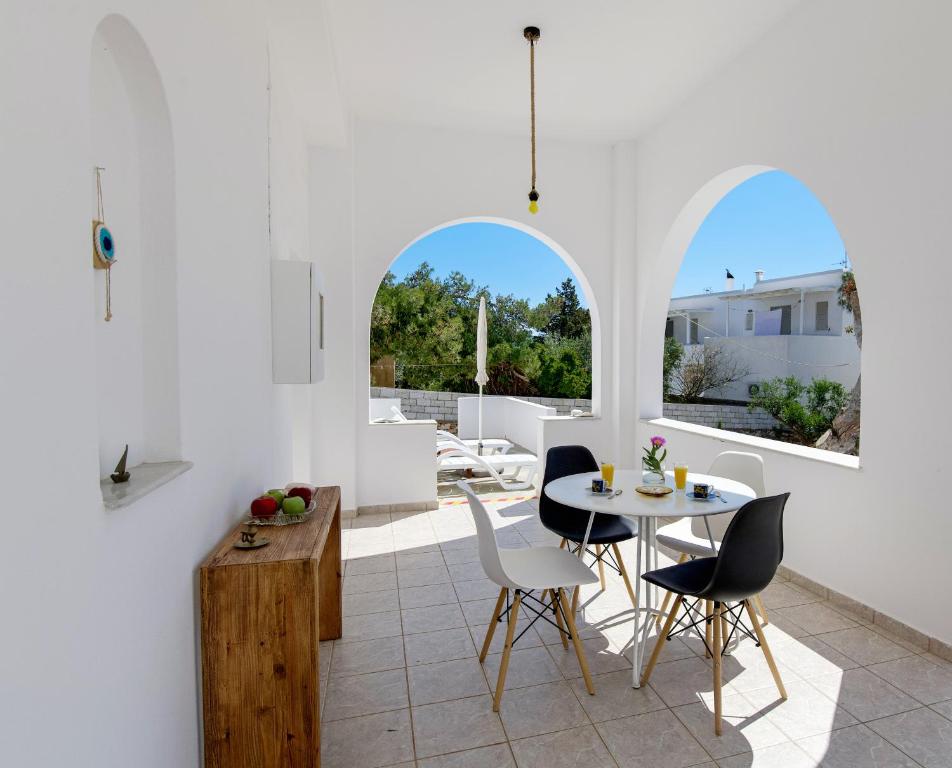 Il comprend une cuisine et une salle à manger avec des murs blancs, une table et des chaises. dans l'établissement Eva House Dryos Beach Paros, à Drios