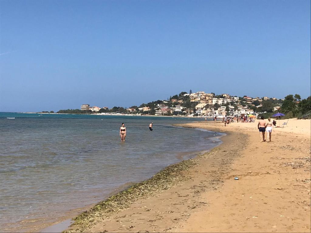 un groupe de personnes marchant sur la plage dans l'établissement Marea affittacamere, à Porto Empedocle