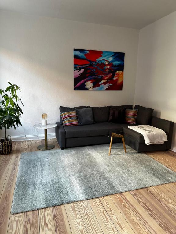 ein Wohnzimmer mit einem schwarzen Sofa und einem Teppich in der Unterkunft Großzügige 3-Zimmer Altbauwohnung in Kiel