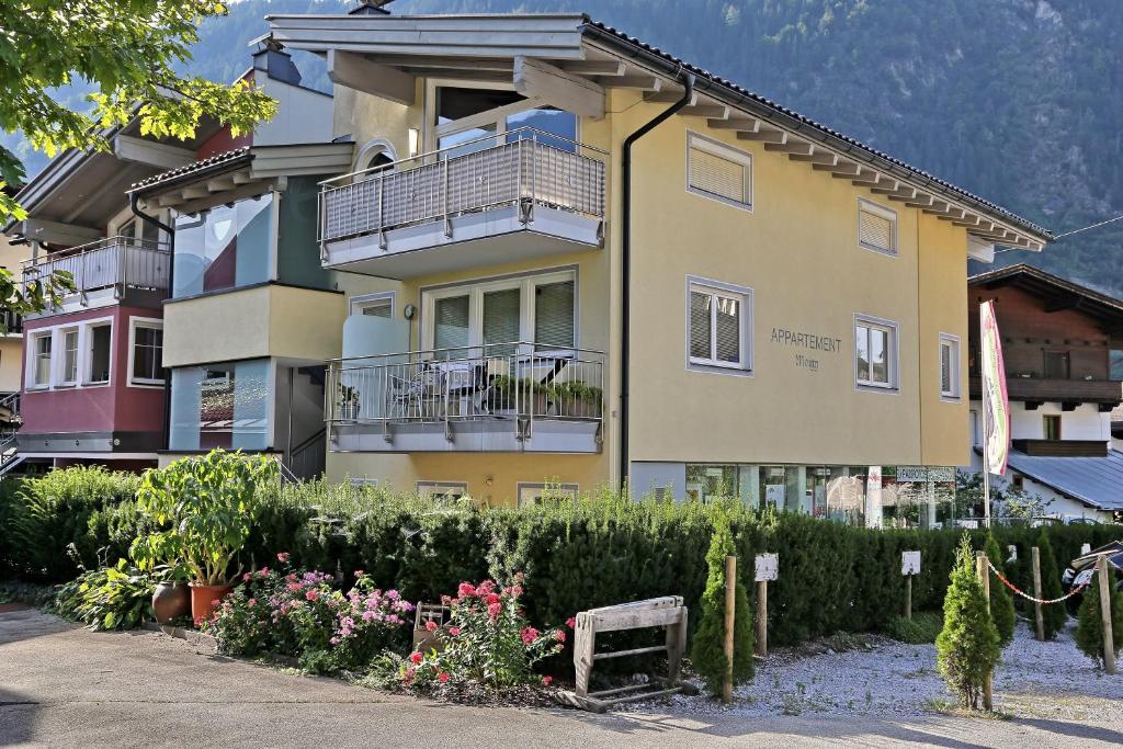 een geel gebouw met een balkon en een aantal bloemen bij Alpen Appartements MOIGG in Mayrhofen