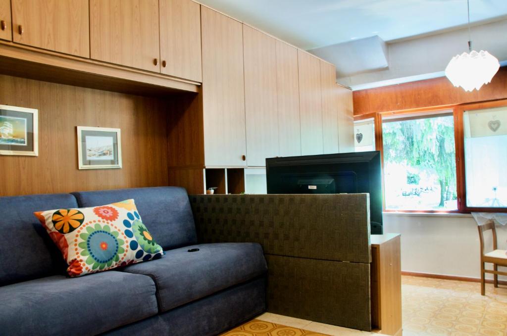 sala de estar con sofá azul y cocina en Al Sole di TSS' - Cozy Apartment a 20 Metri dal Lago di Caldonazzo - Perfetto per coppie a Calceranica al Lago, en Calceranica al Lago