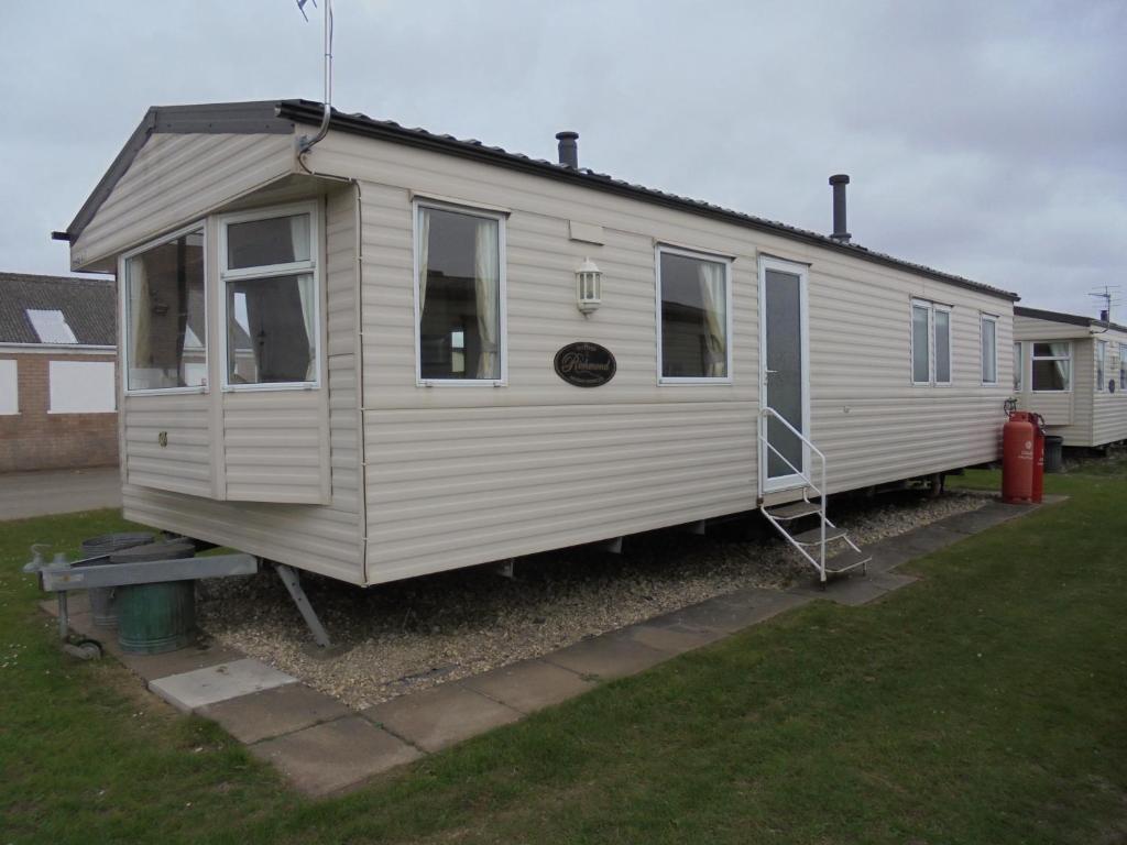 a small white trailer parked in a yard at Coral Beach : The Richmond:- 6 Berth, Blow heated in Ingoldmells