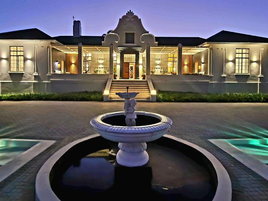 ein großes weißes Herrenhaus mit einem Brunnen davor in der Unterkunft PJURE Wellness Retreat & Spa in Montagu