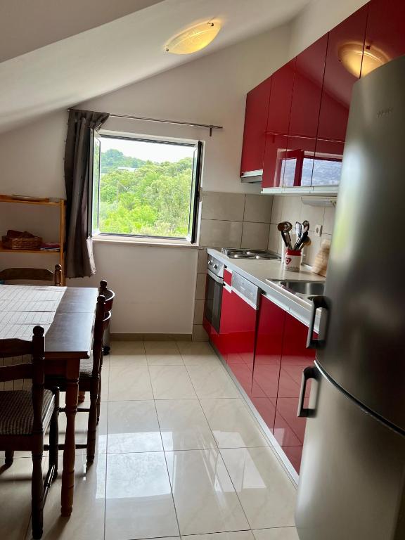 a kitchen with red cabinets and a table and a window at Apartmani Luka in Korčula