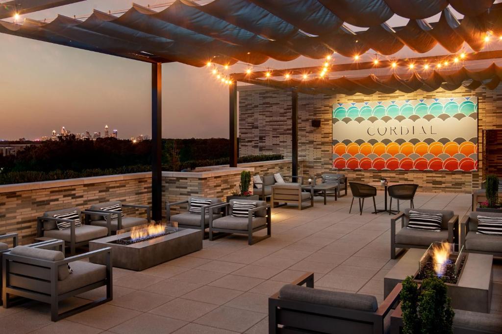 an outdoor patio with chairs and tables and lights at AC Hotel by Marriott Charlotte SouthPark in Charlotte