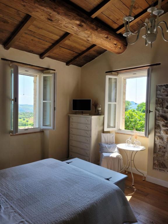 a bedroom with a bed and two windows and a table at B&B L'Usignolo in Ascoli Piceno