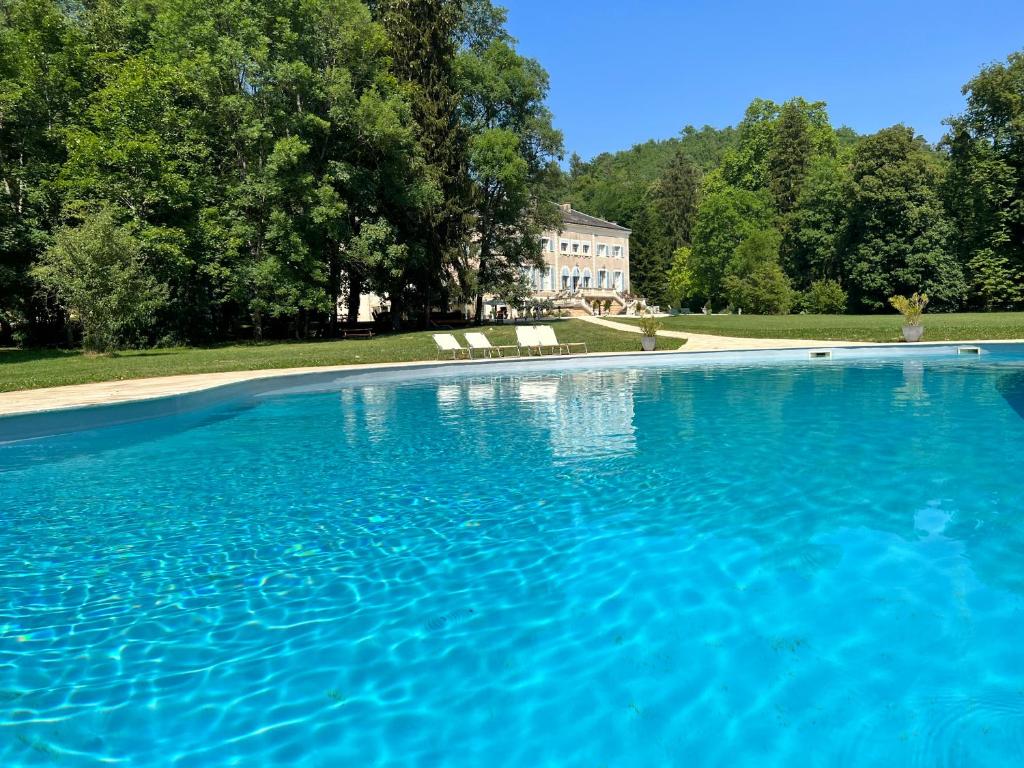 uma grande piscina azul com uma casa ao fundo em Chateau de Rhodes em La Bastide-de-Sérou