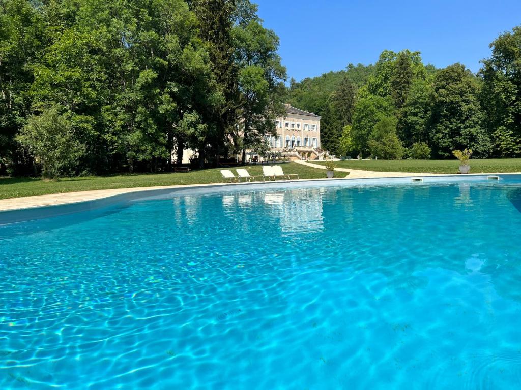 a large blue swimming pool with a house in the background at Chateau de Rhodes in La Bastide-de-Sérou