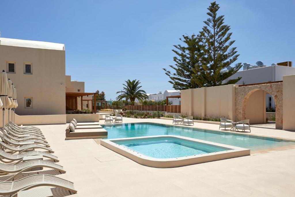 a swimming pool with lounge chairs next to a building at Apricus in Perissa