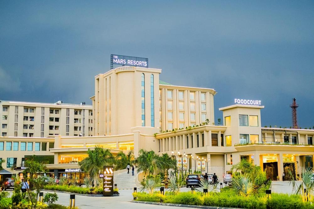 um grande edifício com palmeiras em frente em The Mars Resorts em Meerut