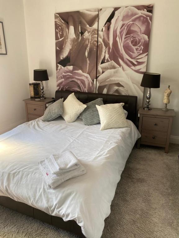 a bedroom with a white bed with a large painting on the wall at THE RODDS in Morley
