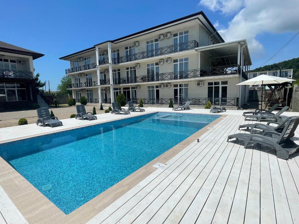 a building with a swimming pool in front of a building at Бугенвиллея in Lidzava