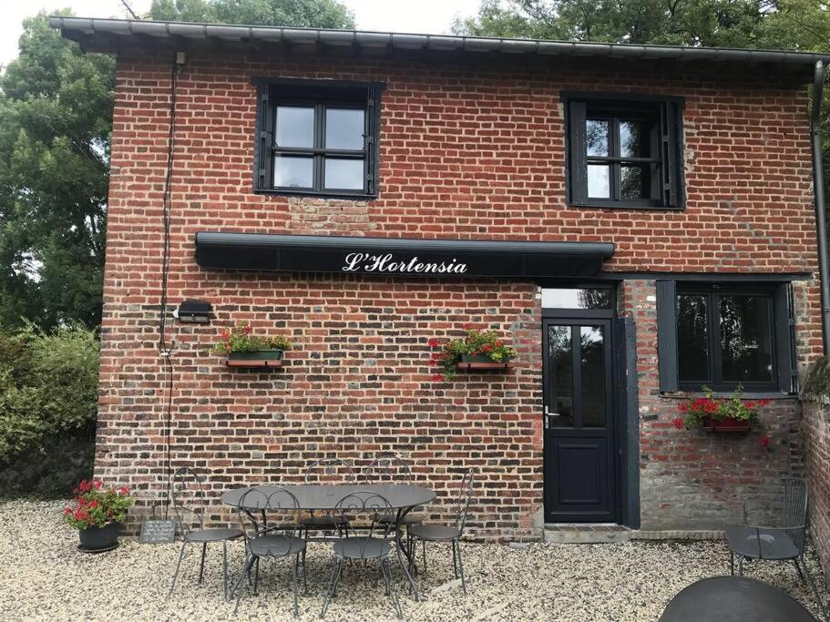a brick building with a table in front of it at L'Hortensia in Beuvron-en-Auge